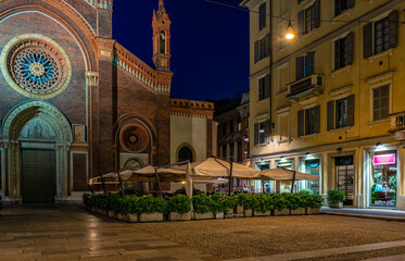 Old square with restaurant tables in front of the church Santa Maria del Carmine in Milan, Italy. Night cityscape of Milan. Architecture and landmarks of Milan. - obrazy, fototapety, plakaty