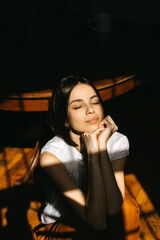 Young brunette woman portrait in direct sunlight, indoors.