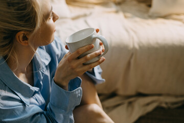 Contemplative moment with coffee. Closeup of a woman holding a white mug of coffee in hands.