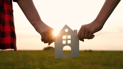 hands holding paper house, window sunset ray, happy family mortgage build new house, building a new...