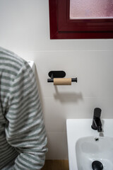 Unrecognizable man in the bathroom who has run out of toilet paper. Trouble for a man who is urgently using the toilet.