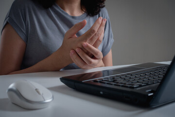 woman holding her wrist pain from using a laptop computer long time. Carpal tunnel syndrome or...