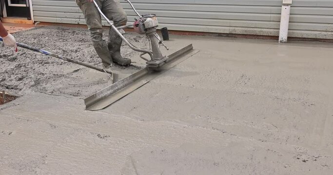Construction worker uses special tool to level concrete