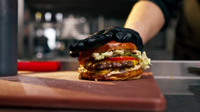 close-up of the hand in restaurant attaching one half of bun to the other a ready-made burger