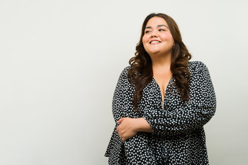 Smiling plus-size woman poses in a studio setting and looks towards copy space - 790415917