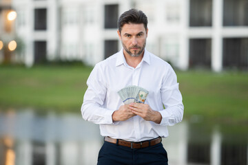Attractive man is holding cash money in one hand. Joyful man with banknotes of money in his hands....