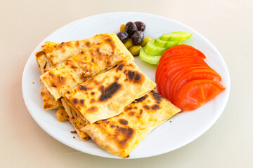 Freshly baked appetizing Turkish tortillas -Gozleme with spinach, cheese  on a wooden board. Shallow depth of  field. Handmade Turkish traditional pastries. Otlu peynirli ispanakli gozleme.