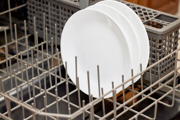 Close up of a white ceramic bowl in the lower rack of a dishwasher