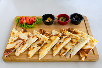 Freshly baked appetizing Turkish tortillas -Gozleme with spinach, cheese  on a wooden board. Shallow depth of  field. Handmade Turkish traditional pastries. Otlu peynirli ispanakli gozleme.