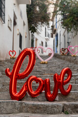 Stone stairs of a city street decorated with puffy heart-shaped balloons and letters composing the word "love".