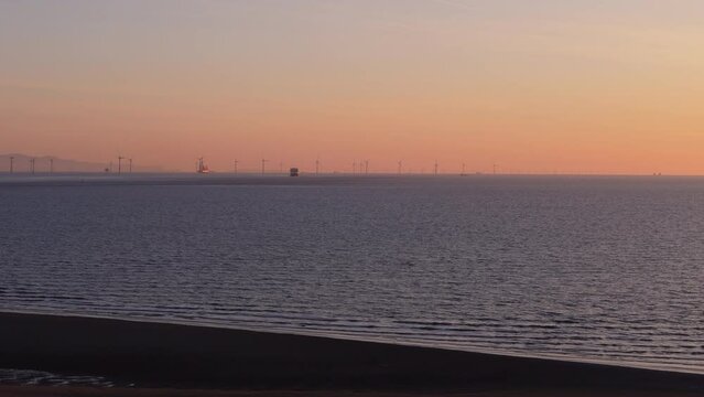 Aerial view of offshore wind farm at sunset 