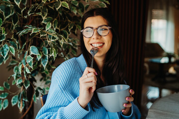 One young caucasian woman is eating breakfast at home before work