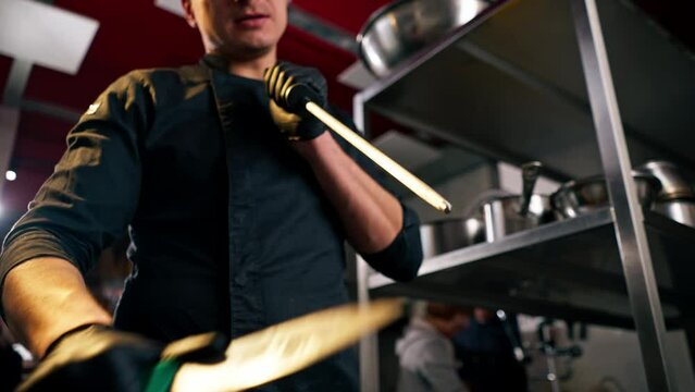 the chef stands in the kitchen in black jacket and sharpens his knives before cooking something tasty