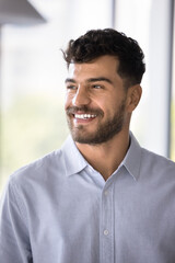 Cheerful handsome Arab professional man in formal shirt looking away with toothy smile. Happy successful young businessman, project manager, entrepreneur vertical portrait
