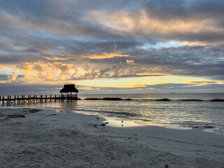 sunrise over a covered dock along the beach