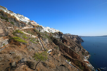 The amazing town of Fira, Santorini, perched on the clifftop of the volcanic caldera, with a steep flight of steps leading down to the old harbor - Greece - obrazy, fototapety, plakaty