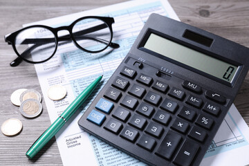 Tax accounting. Calculator, document, pen and coins on wooden table, closeup