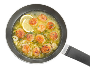 Delicious scallops with sauce in frying pan isolated on white, top view