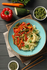 Vegetarian meal. Tasty pasta and fresh vegetables on dark wooden table, flat lay