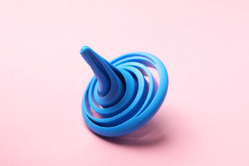 One blue spinning top on pink background, closeup