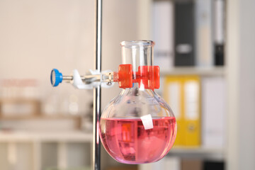 Laboratory analysis. Glass flask with pink liquid on stand indoors, closeup