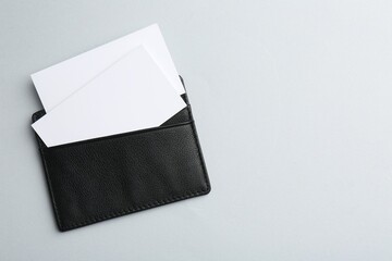 Leather business card holder with blank cards on light grey background, top view. Space for text