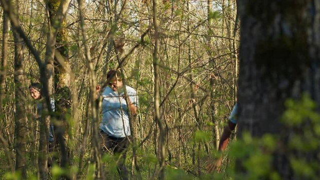Group of lifesavers volunteers searching for a missing person, calling their name in the woods and going through the trees to track steps. Search squad rescuers looking for a lost victim. Camera A.