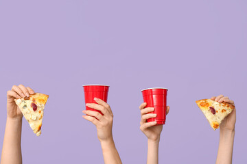 Many hands holding tasty pizza slices and one-use cups on lilac background