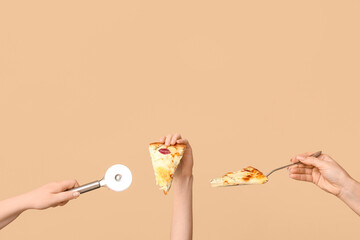 Many hands holding pizza slices and pizza cutter on beige background