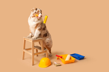 Cute dog and decorator's tools on beige background