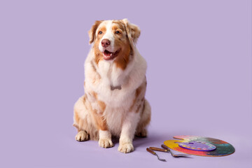 Cute dog with artist's supplies on lilac background