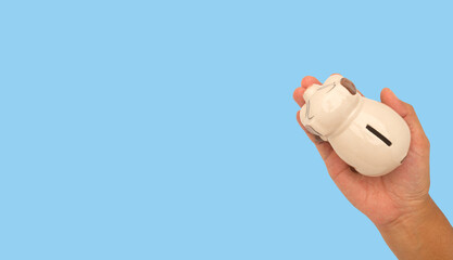 Top view of a hand holding a piggy bank against a blue background.
