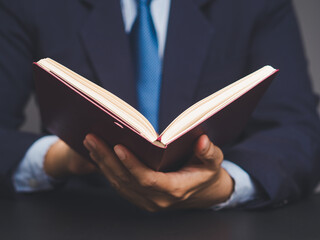 Businessman reading a book while sitting at a desk.
