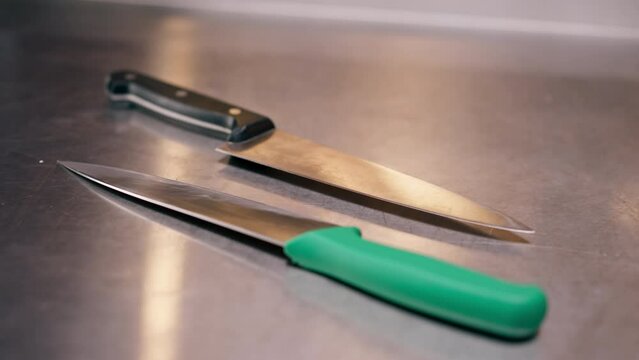 close-up of large slicing knives lying on a metal table in professional kitchen