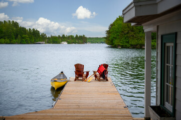Resting on a Muskoka cottage dock, two Adirondack chairs oversee the serene expanse of an Ontario...