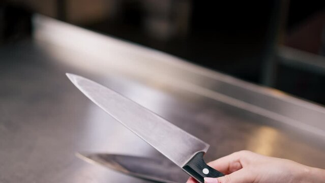 close-up in a professional kitchen a girl's hand tests a new slicing knife