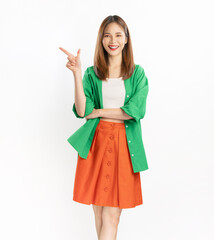 Cheerful Asian woman wearing a green shirt smiles as she points to the side with her hand, isolated on a white background.