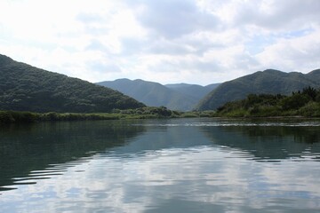 Fototapeta na wymiar A panoramic view of mountains and dense forests from the river in Amami Oshima Island