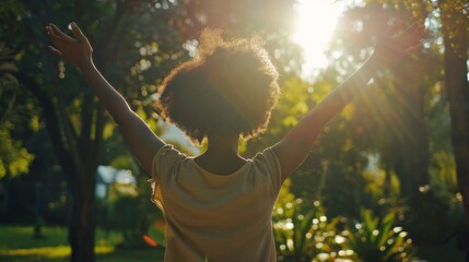 Black woman raising her arms in the air, surrounded by trees - obrazy, fototapety, plakaty