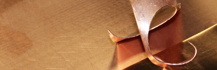  Copper pieces of metal on a table, close-up. Twisted chips cut from a copper sheet close up....