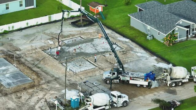 Construction of concrete foundation slab at new house developing site. Workers pouring concrete bedding ready for building future walls and roof