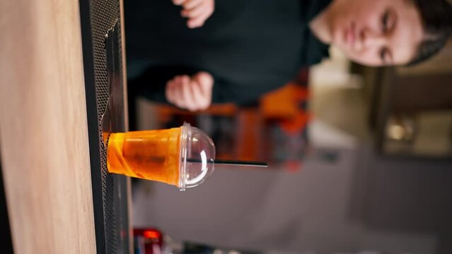 vertical video close-up in a professional kitchen behind the bar girl puts a drink and inserts a straw