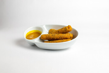 A plate of food with a yellow dipping sauce and three pieces of food