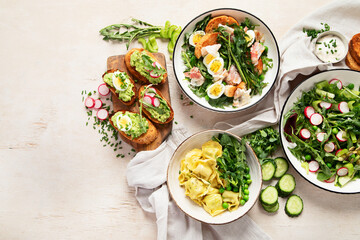 Spring fresh food with green leaf. Salads with strawberries, bacon and ravioli on light wooden background