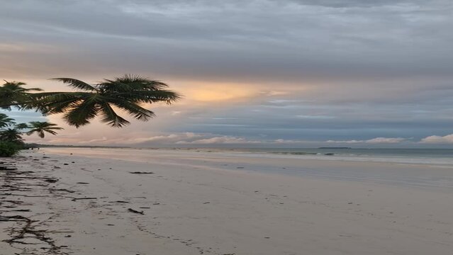 Weißer Sandstrand bei Sonnenaufgang auf Sansibar in Tansania mit bewölktem Himmel