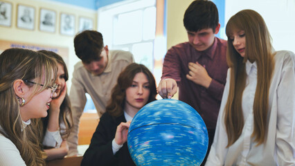 Students look at a globe of the starry sky in a classroom at school.