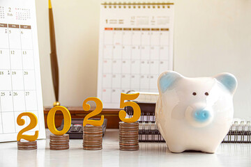 2025 New year saving money and financial planning concept. gold wooden number 2025 on a stack of...