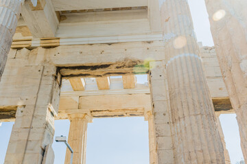 Sunlight flares over ancient Greek architectural ruins with sky in the background, in Athens Greece