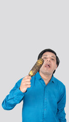 portrait view of a Indian young male eating a corn cob with style, copy space on top side