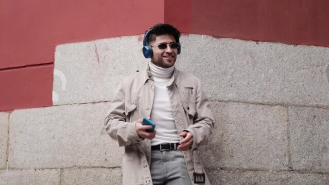 Stylish colombian young man using phone to listen to music and dance.